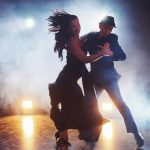 Skillful dancers performing in the dark room under the concert light and smoke