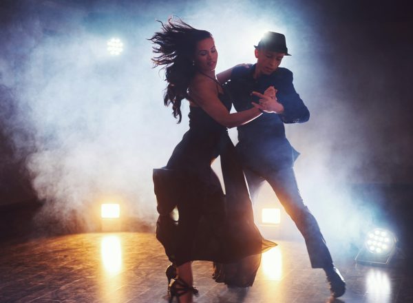 Skillful dancers performing in the dark room under the concert light and smoke